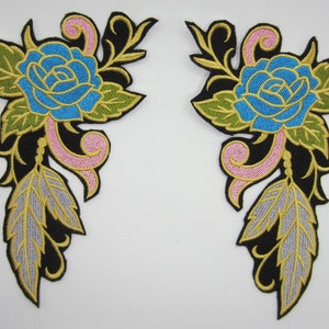 May include: Two embroidered iron-on patches featuring a blue rose with gold and green leaves, pink swirls, and silver feathers on a black background.