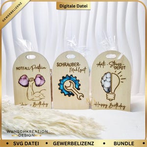 Könnte beinhalten: Drei Holz-Geschenkanhänger mit gewölbten Oberteilen. Jeder Anhänger zeigt ein anderes Design: einen Gewichtheber mit dem Text "NOTFALL-Protein", einen Schraubenschlüssel und ein Zahnrad mit "SCHRAUBER-Mahlzeit" und ein Gehirn in einer Glühbirne mit "Anti-Stress-DEPOT".