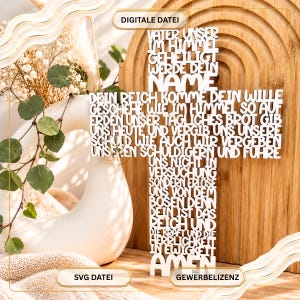 May include: A white cross-shaped wall decoration featuring the German text of the Lord's Prayer cut out in a bold, sans-serif font. The text includes the words Vater Unser, Geheiligt Werde Dein Name, and Amen. The piece is displayed vertically.