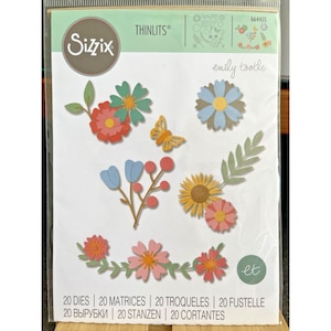 Pode incluir: Um conjunto de matrizes de corte Sizzix Thinlits com flores e uma borboleta de papel coloridas. A embalagem apresenta o texto "emily tootle" e "20 DIES | 20 MATRICES | 20 TROQUELES | 20 FUSTELLE". As formas cortadas são ideais para artesanato.