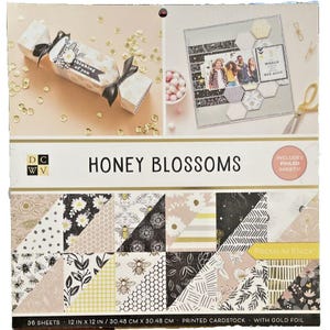 Puede incluir: Un paquete de cartulina impresa Honey Blossoms con lámina dorada. El paquete incluye 36 hojas de 30,48 cm x 30,48 cm. El diseño presenta patrones florales y de abejas en negro, blanco y dorado.