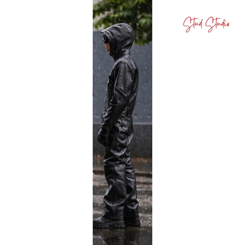 Puede incluir: Un mono negro con capucha, guantes y botas. La prenda de una pieza est&aacute; hecha de un material texturizado, posiblemente cuero o una tela similar al cuero. La persona est&aacute; de pie bajo la lluvia, con gotas de agua visibles.