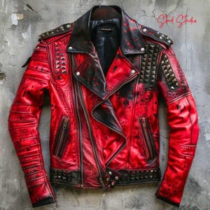 May include: A red leather jacket with black accents and metal stud embellishments. The jacket features a classic biker style with a notched collar, asymmetrical zipper, and multiple pockets. The sleeves have ribbed detailing, and the jacket is hanging on a hanger.