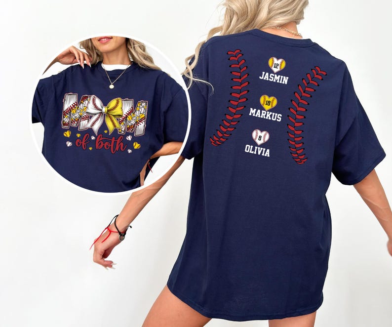 Pu&ograve; includere: Una t-shirt blu navy con una grafica frontale raffigurante un fiocco da baseball e softball e il testo "MOM of both". Il retro mostra un motivo a cuciture da baseball con tre palline a forma di cuore etichettate con i nomi "JASMIN", "MARKUS" e "OLIVIA".