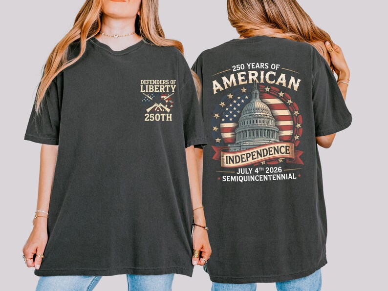 May include: Dark grey t-shirt with "Defenders of Liberty" and "250th" printed on the front. The back features a design commemorating 250 years of American Independence, including the Capitol building, the American flag, and the date July 4th, 2026.