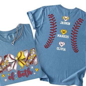 Pu&ograve; includere: Una t-shirt blu con una grafica frontale che riporta il testo MOM OF BOTH e un fiocco da softball giallo e bianco. La grafica sul retro mostra due motivi di cuciture da baseball rossi che incorniciano tre softball a forma di cuore con i nomi JASMIN, MARKUS e OLIVIA.