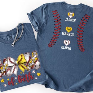 Pu&ograve; includere: Una t-shirt blu con una grafica della parola MOM con un fiocco da softball giallo e bianco, e il testo of both. Il retro della maglietta mostra cuciture da softball rosse, tre cuori con i numeri 12, 18, 8 e i nomi JASMIN, MARKUS, OLIVIA.