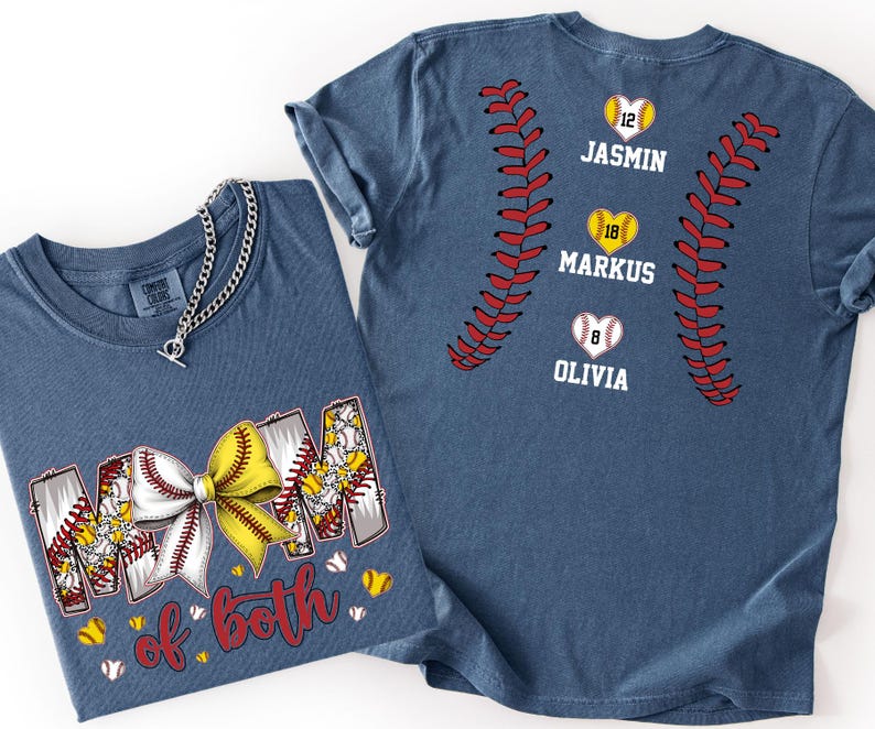 Pu&ograve; includere: Una t-shirt blu con una grafica della parola MOM con un fiocco da softball giallo e bianco, e il testo of both. Il retro della maglietta mostra cuciture da softball rosse, tre cuori con i numeri 12, 18, 8 e i nomi JASMIN, MARKUS, OLIVIA.