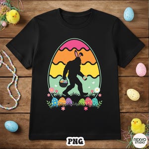 May include: Black t-shirt featuring a Bigfoot silhouette wearing bunny ears and carrying Easter eggs in a basket. The design includes a colorful egg-shaped background and Easter eggs at the bottom. The shirt has a crew neck.