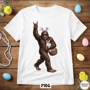 May include: White t-shirt featuring a Bigfoot character wearing bunny ears and sunglasses, holding a white rabbit and a basket of Easter eggs. The Bigfoot is making a rock and roll hand gesture. The shirt has a PNG logo.