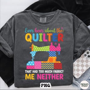 May include: Dark gray long-sleeve shirt with a colorful graphic of a sewing machine made of quilt blocks. The text reads "Ever hear about the: QUILTER THAT HAD TOO MUCH FABRIC? ME NEITHER." The shirt has a vintage, washed look.