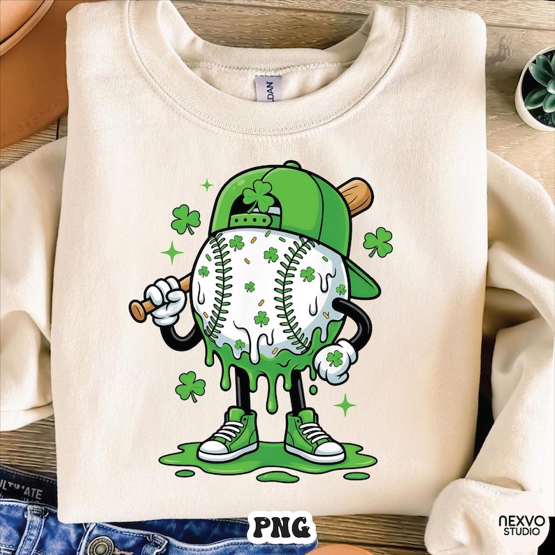 K&ouml;nnte beinhalten: Cremefarbenes Sweatshirt mit einem Baseball-Charakter zum St. Patrick's Day. Der Baseball ist wei&szlig; mit gr&uuml;nen Kleebl&auml;ttern und gr&uuml;nen Tropfenakzenten. Die Figur tr&auml;gt eine gr&uuml;ne Baseballkappe und gr&uuml;ne Turnschuhe und h&auml;lt einen Holzschl&auml;ger.