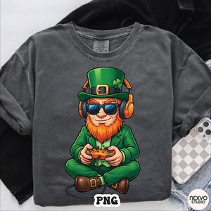 May include: Dark gray t-shirt featuring a cartoon leprechaun wearing a green suit, hat, and sunglasses, with orange headphones. The leprechaun is holding a game controller. The word "PNG" is at the bottom.