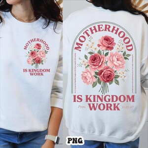 Peut inclure: Sweat-shirt blanc avec un bouquet de roses roses et le texte "MOTHERHOOD IS KINGDOM WORK." Le dos du sweat-shirt reprend le motif avec du texte suppl&eacute;mentaire, dont "Prov. 31:25-27."