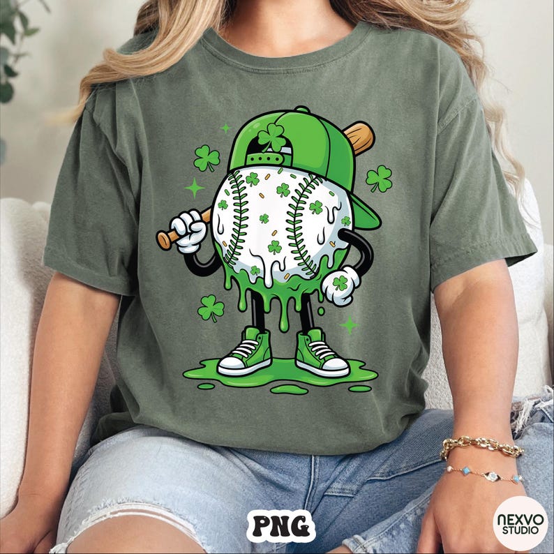 K&ouml;nnte beinhalten: Gr&uuml;nes T-Shirt mit einer Cartoon-Baseballfigur mit gr&uuml;ner Baseballkappe und Holzschl&auml;ger. Der Baseball ist wei&szlig; mit gr&uuml;nen Kleebl&auml;ttern und gr&uuml;nen tropfenden Akzenten. Die Figur tr&auml;gt gr&uuml;ne Turnschuhe.