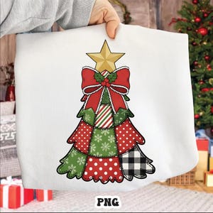 Könnte beinhalten: Weißes Sweatshirt mit einem Weihnachtsbaum-Design. Der Baum besteht aus Patchwork-Mustern in Rot, Grün und Schwarz, verziert mit einem goldenen Stern und einer roten Schleife. Das Wort "PNG" ist unten sichtbar.