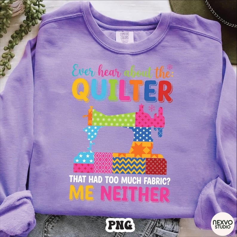 May include: A lilac-colored sweatshirt with the text "Ever hear about the QUILTER that had too much fabric? ME NEITHER." A colorful patchwork sewing machine graphic is centered below the text. The sweatshirt is made of a soft material.