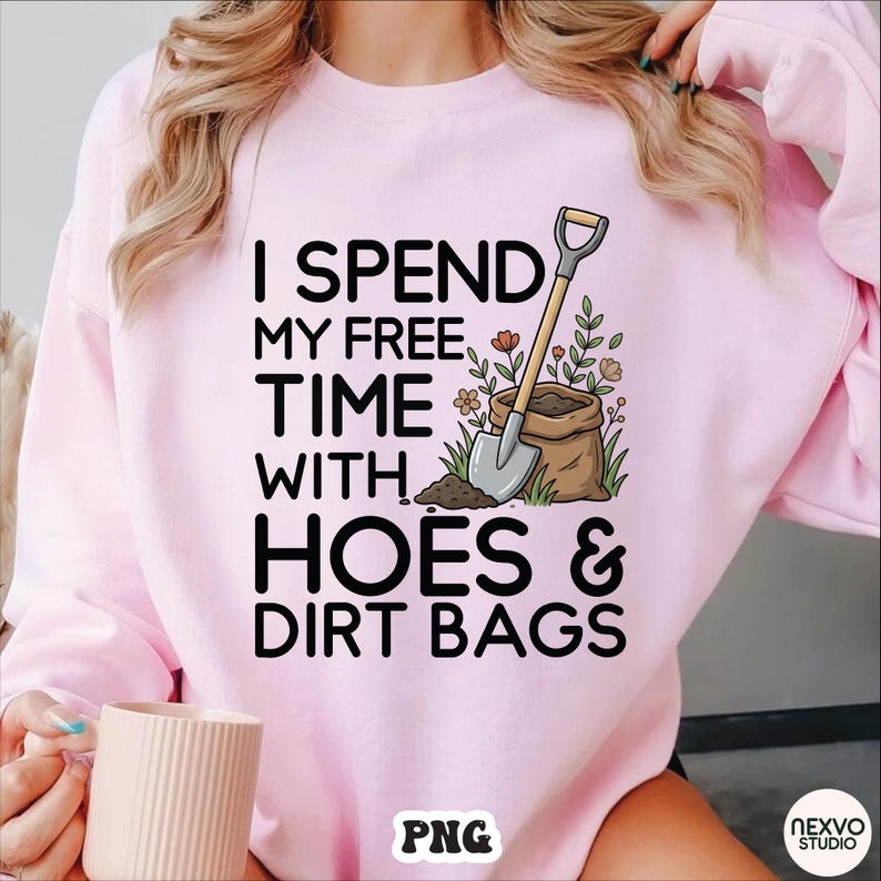 May include: A light pink sweatshirt with the text "I SPEND MY FREE TIME WITH HOES & DIRT BAGS" in black. The graphic includes a shovel, a bag of soil, and flowers. The sweatshirt is a casual garment.