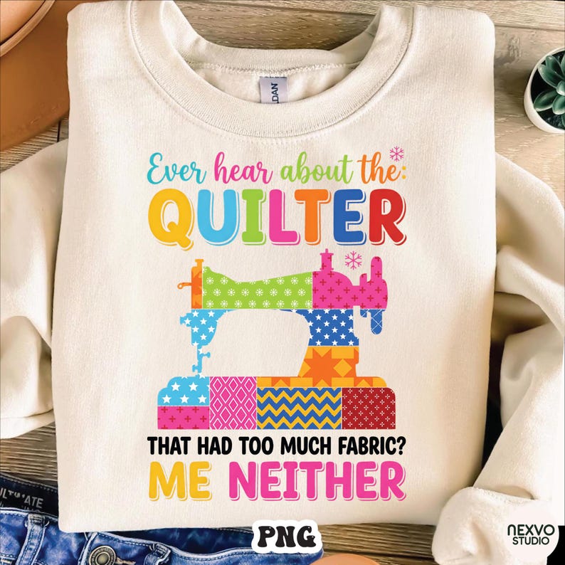 May include: Cream-colored sweatshirt with a colorful graphic of a sewing machine and the text "Ever hear about the QUILTER that had too much fabric? ME NEITHER." The sewing machine design incorporates various patterns and colors.