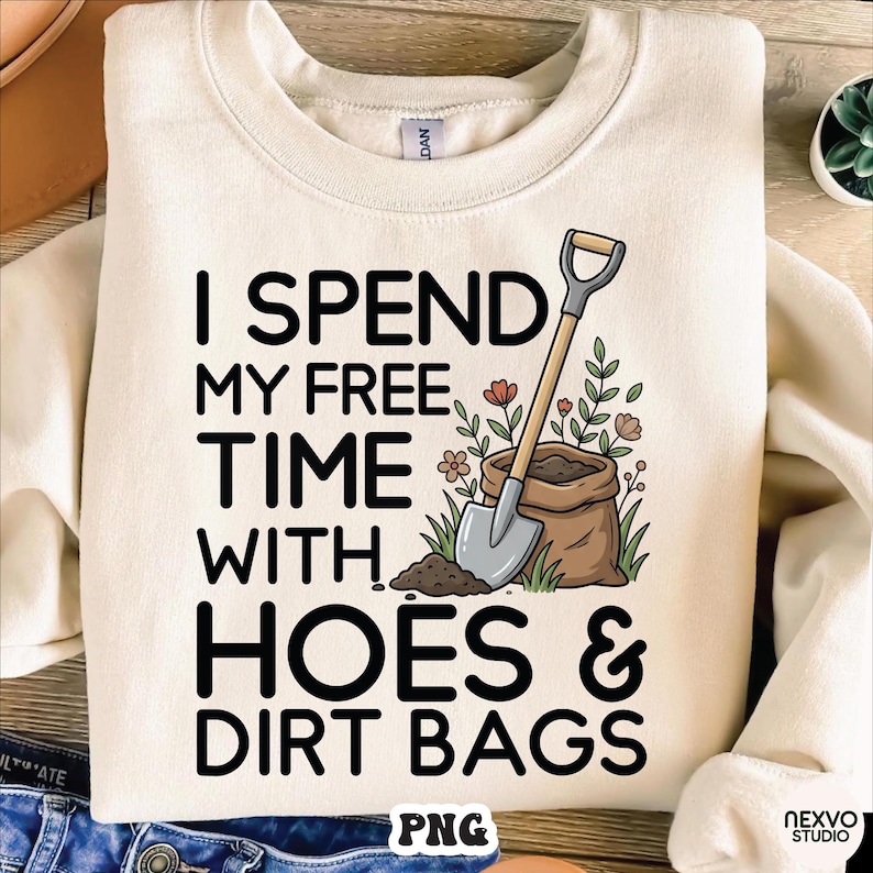 May include: Cream-colored sweatshirt with the text "I Spend My Free Time With Hoes & Dirt Bags" in black. A shovel, a bag of soil, and flowers are illustrated on the right side of the text. The word "PNG" is at the bottom.