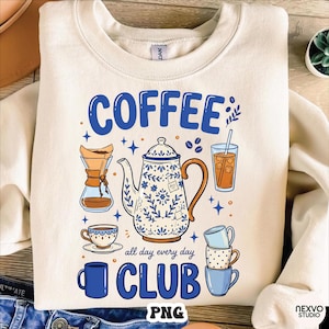 May include: Cream-coloured sweatshirt with a blue and white coffee-themed graphic. The design includes a teapot, coffee cups, and the words "COFFEE CLUB" and "all day every day".