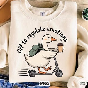 May include: Cream-colored sweatshirt with a graphic of a goose riding a scooter, holding a coffee cup, and wearing a backpack. The text "Off to regulate emotions" is arched above the goose. The bottom right corner has the text "NEXVO STUDIO" and "PNG".