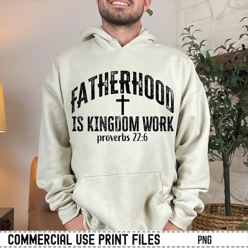 May include: A cream-colored hoodie with the text "FATHERHOOD IS KINGDOM WORK" in black, with a cross symbol and the Bible verse Proverbs 22:6. The hoodie has a drawstring hood and a front pocket.