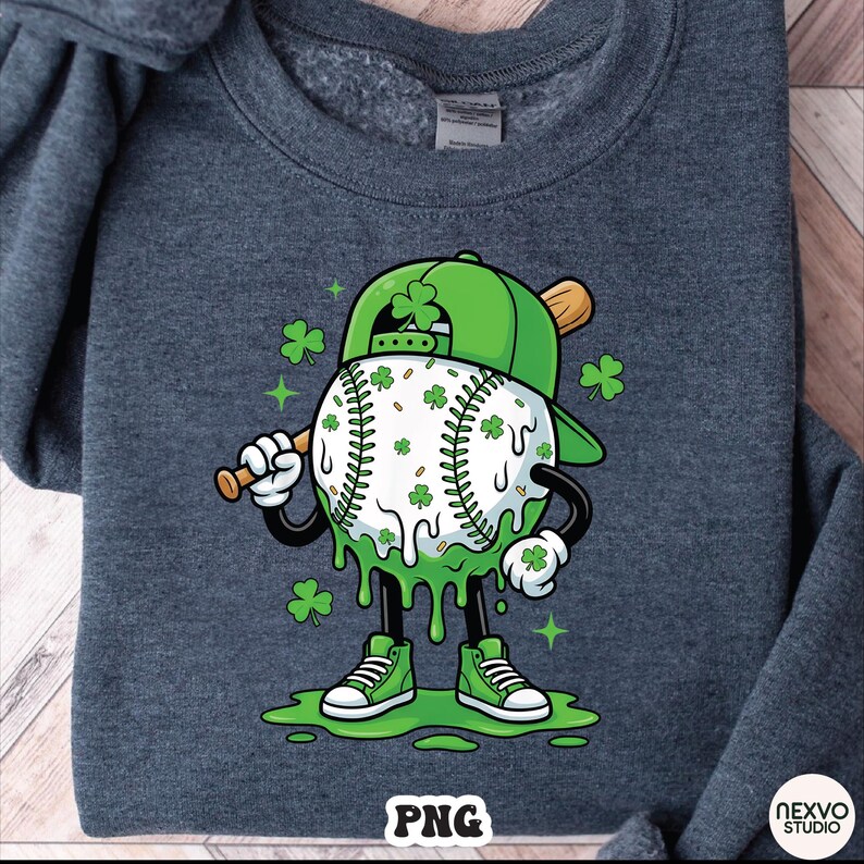 K&ouml;nnte beinhalten: Dunkelgraues Sweatshirt mit einer Cartoon-Baseballfigur mit gr&uuml;ner Baseballkappe und Kleebl&auml;ttern. Der Baseball ist wei&szlig; mit gr&uuml;nen Kleebl&auml;ttern und tropfenden gr&uuml;nen Akzenten. Die Figur h&auml;lt einen Holzschl&auml;ger und tr&auml;gt gr&uuml;ne Turnschuhe.