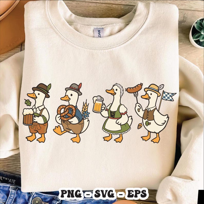 May include: Cream-colored sweatshirt featuring a cartoon illustration of four ducks dressed in traditional Bavarian attire. Each duck is holding items like beer, pretzels, and sausages, with the text "PNG SVG EPS" at the bottom.