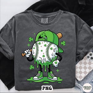 K&ouml;nnte beinhalten: Dunkelgraues Langarmshirt mit einer Cartoon-Baseballfigur, die eine gr&uuml;ne Kappe und Schuhe tr&auml;gt und einen Schl&auml;ger h&auml;lt. Der Baseball ist mit Kleebl&auml;ttern und gr&uuml;nem Schleim verziert. Das Wort "PNG" steht unten.