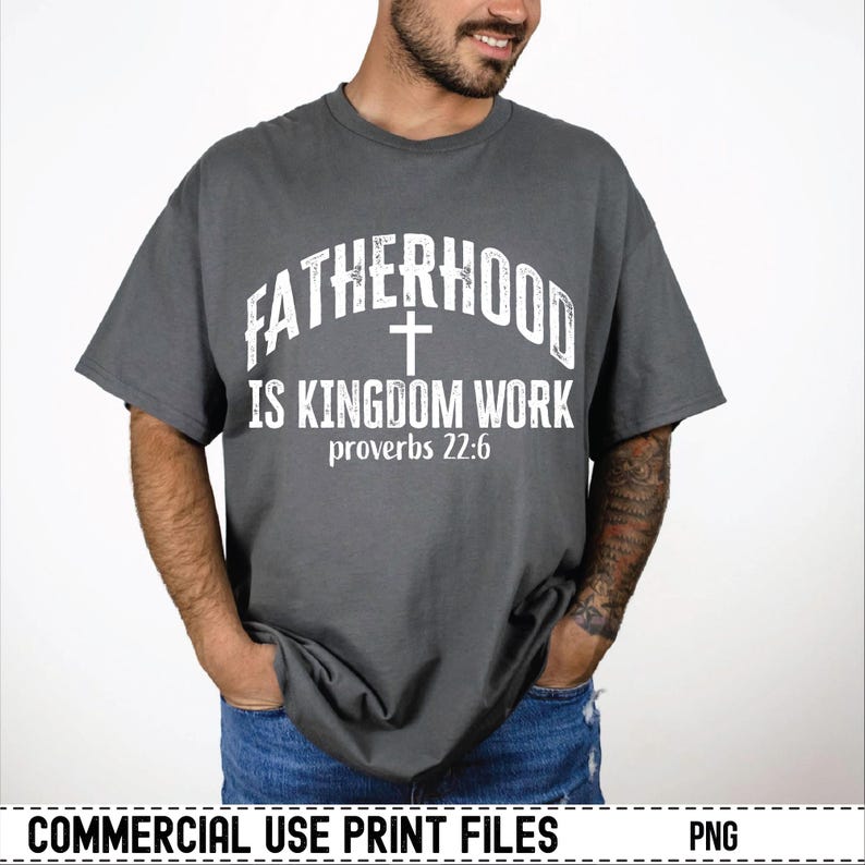 May include: A gray t-shirt with the text "FATHERHOOD IS KINGDOM WORK" in white, along with a cross and the Bible verse Proverbs 22:6. The shirt is a casual style, suitable for everyday wear.