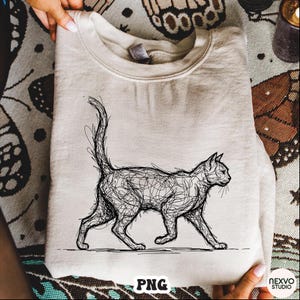 Puede incluir: Sudadera beige con un dibujo lineal negro de un gato caminando. El gato está representado con líneas garabateadas. La palabra "PNG" es visible en la parte inferior izquierda de la prenda.