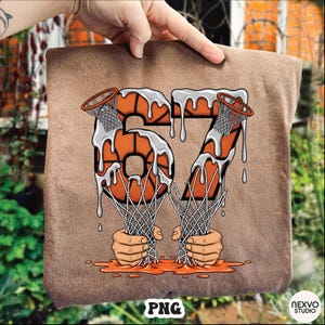 May include: A brown t-shirt featuring a basketball-themed graphic. The number "67" is designed with basketballs and nets, with a dripping effect. The bottom of the graphic shows two hands holding the nets. The bottom right corner has the text "NEXVO STUDIO".