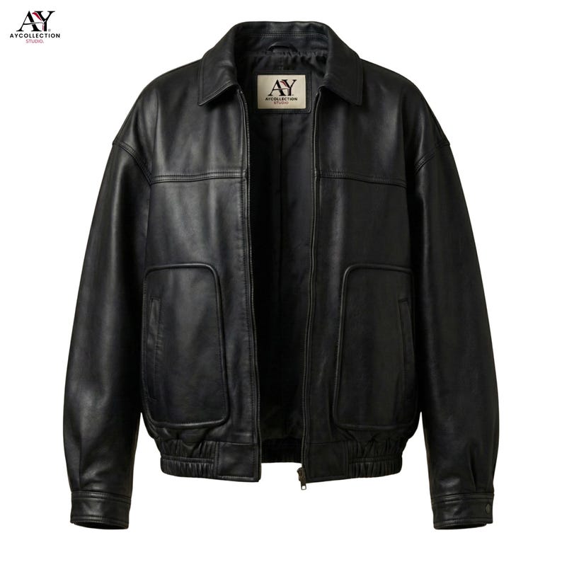 Puede incluir: Chaqueta de cuero negra con cuello, bolsillos delanteros y cierre de cremallera. La chaqueta tiene un estilo bomber cl&aacute;sico con pu&ntilde;os y dobladillo acanalados. El logotipo de la marca "AY COLLECTION STUDIO" es visible en la esquina superior izquierda.