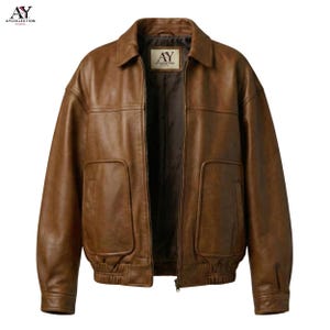 Puede incluir: Chaqueta de cuero marr&oacute;n con cuello, dos bolsillos delanteros y cierre de cremallera. La chaqueta tiene un estilo bomber cl&aacute;sico con dobladillo y pu&ntilde;os de canal&eacute;. La etiqueta dice "AY COLLECTION STUDIO".