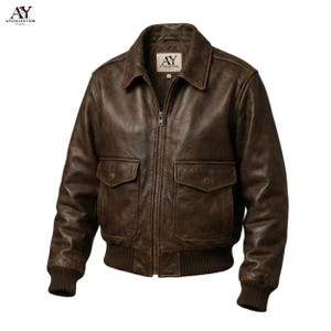 May include: A brown leather bomber jacket with a zip-up front, two front pockets, and a ribbed hem and cuffs. The jacket has a classic collar and a distressed finish, giving it a vintage look. The label on the jacket reads "AY Collection Studio".