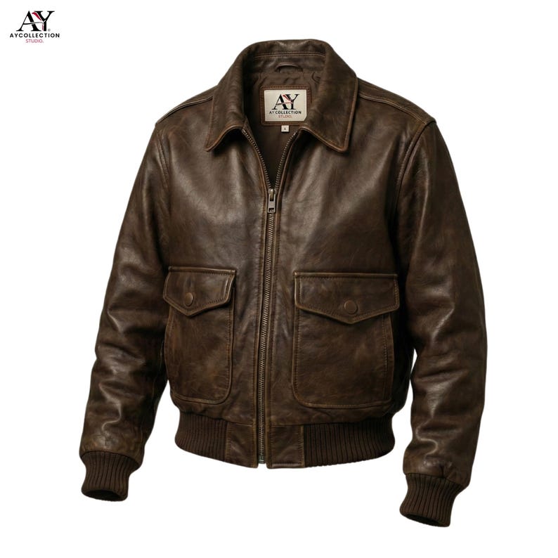 May include: A brown leather bomber jacket with a zip-up front, two front pockets, and a ribbed hem and cuffs. The jacket has a classic collar and a distressed finish, giving it a vintage look. The label on the jacket reads "AY Collection Studio".