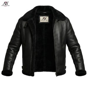 May include: Black leather jacket with a shearling lining and a wide collar. The jacket has a zipper closure, two side pockets, and a logo patch. The cuffs and collar are trimmed with black shearling. The jacket is from AYCollection Studio.