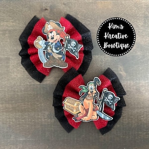 May include: Two red and black hair bows with a pirate theme. One bow features Mickey Mouse dressed as a pirate holding a treasure chest. The other bow features Pluto dressed as a pirate holding a treasure chest and a sword. The bows are decorated with black and white pirate flags.