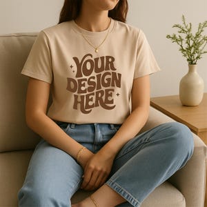Beige T-Shirt Mockup On Woman Sitting Indoors | Minimalist Bella Canvas Style Tee Mockup | Beige Bella Canvas 3001 Style Shirt Mockup