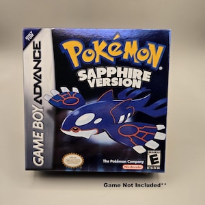 May include: A Game Boy Advance game box for Pokémon Sapphire Version. The box is predominantly dark blue with the Pokémon logo in yellow and the game title in white. A blue and white creature is featured prominently.