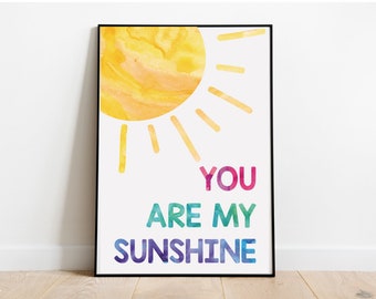 May include: A watercolor print with a yellow sun and the text "YOU ARE MY SUNSHINE" in rainbow colors.