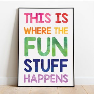 Puede incluir: Una impresión enmarcada con fondo blanco y texto colorido que dice "This is where the fun stuff happens". El texto está en un degradado arcoíris, comenzando con rosa y terminando con morado.