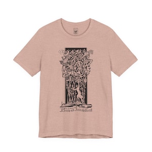 May include: A light pink t-shirt featuring a black and white illustration. The graphic includes an ornate design with a figure and the text "Ex Libris Birojmené". The shirt has short sleeves and a crew neck.
