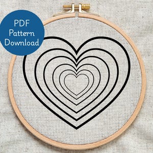 May include: An embroidery hoop with a cross-stitch design of black concentric hearts. The design is on a light-coloured fabric. A blue circle with the text "PDF Pattern Download" is in the upper left corner.