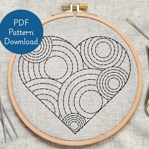 Könnte beinhalten: Stickrahmen mit einem herzförmigen Design aus schwarz genähten Kreisen und Bögen. Der Text "PDF Pattern Download" befindet sich auf einem blauen Kreis. Enthält Nadeln und eine goldene Schere.