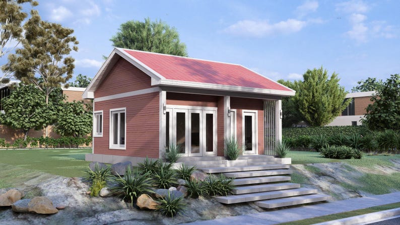 May include: A small, red-brown house with a red roof and white trim. The house has a porch with white doors and windows. Steps lead up to the porch. Landscaping includes green plants and grass. The sky is blue with some clouds.