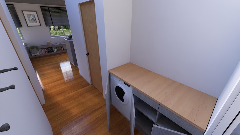 May include: Interior view of a utility room with a washing machine and a wooden countertop. The room has a light colour scheme with wooden flooring and a door leading to another room. A framed picture hangs on the wall.