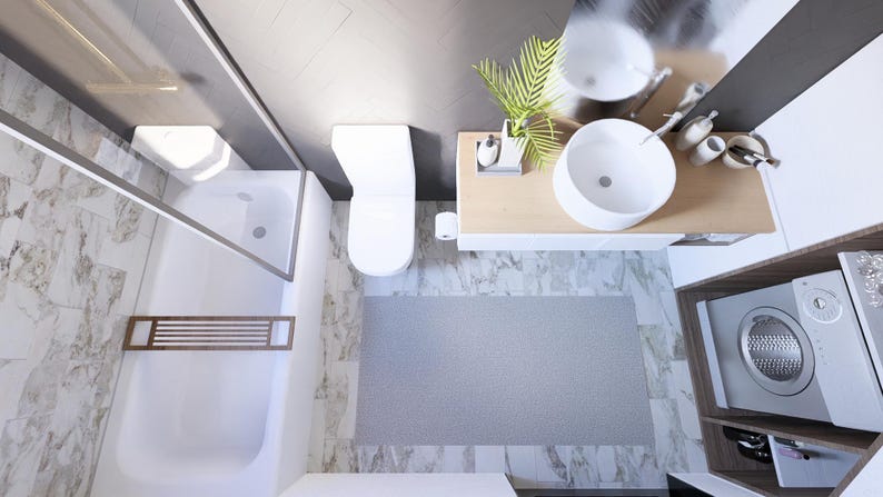 May include: An overhead view of a modern bathroom with a white toilet, sink, and shower. A grey rug sits on the floor. A washing machine is in a wooden cabinet. The walls are marble and grey.