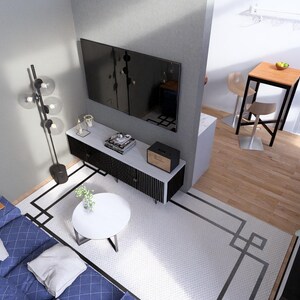 May include: An overhead view of a modern living room with a blue sofa, white rug, and a black and white entertainment center. A large flat-screen TV is mounted on the wall above the entertainment center. A small table and chairs are in the background.